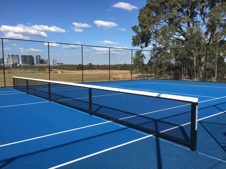 Blue tennis court at George Kendall Riverside Reserve with the Parramatta skyline behind