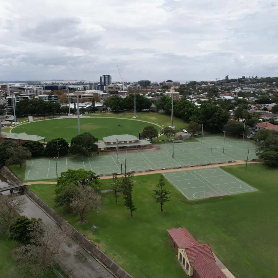 Aerial view of a large netball court complex at National Park, Newcastle, with the city and harbour behind